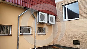 Under the roof of metal roof over the windows with louvers on the wall of the building on metal supports are installed air conditi