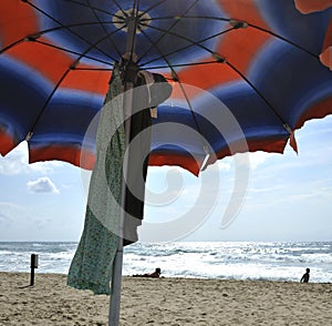 Under the umbrella on the beautiful Sabaudia beach. In the background an attractive woman sunbathing.