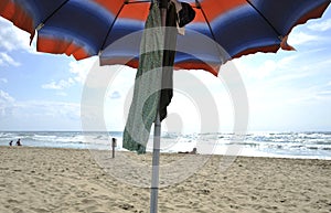 Under the umbrella on the beautiful Sabaudia beach. In the background an attractive woman sunbathing.