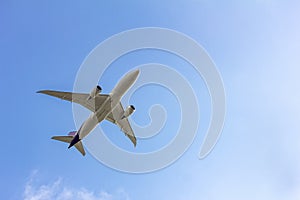 Under view of airplane for commercial passenger or cargo transporation flying on blue sky background with copy space