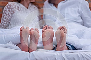 From under the white she covered two pairs of feet of couple in love. The newlyweds are having fun