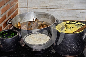 Under the wood stove clay pot containing cooked duck, fried cabbage, rice and cornmeal angu