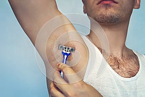 Underarm hair removal. Male depilation. Young attractive muscular man using razor to remove hair from his body. the self-care conc