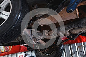 The undercarriage of a car with a jack is lifted for repairs