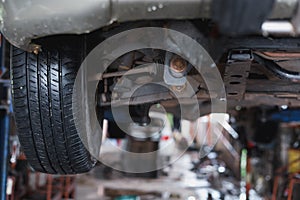 The undercarriage of a car with a jack is lifted for repairs