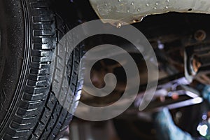 The undercarriage of a car with a jack is lifted for repairs