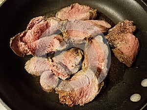 Undercooked beef slices in frying pan or skillet