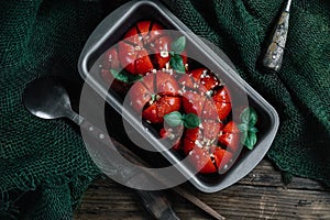 Undercooked tomatoes with spices and chopped garlic before baking on wood background