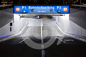 Underground car park entrance with german inscriptions in Luzern. Night view, illuminated by lights. Street signs on the ground