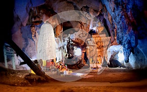 Underground cave in Asia with giant stalagmites, stalactites and giant buddha statue in the center of the hall