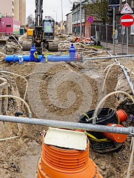 Underground pipe replacement pit on city street, plastic wells, new pipeline with gate valves