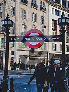 Underground sign subway entry way down stairs trains public transport lamps walk street road houses buildings London