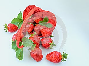 Underlying basket with strawberries spilling on a white