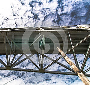 Underneath Sagamore bridge spans Cape Cod Canal under a sky mottled with a heavy cloud cover