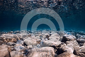 Undersea view with rocks bottom, and blue water. Ocean background