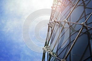 Underside angle view to background of modern glass building skyscrapers over blue sky