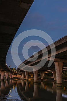 Underside of an elevated road across river at dusk