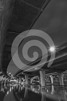 Underside of an elevated road across river at night