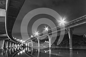 Underside of an elevated road across river at night