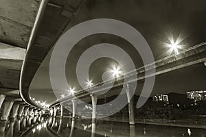 Underside of an elevated road across river at night