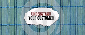 UNDERSTAND YOUR CUSTOMER text on the piece of paper on the green wood background