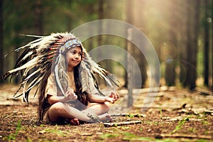 Understanding her heritage from an early age. Full length shot of a little girl meditating while playing dressup in the