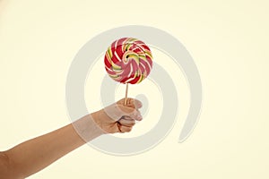 Understanding role sugar young diets. Hand of kid child holds colorful lollipop  white background. Children have