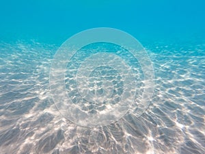 Underwater background with sandy sea bottom. Beautiful texture of the sea and ocean water. Pure water texture