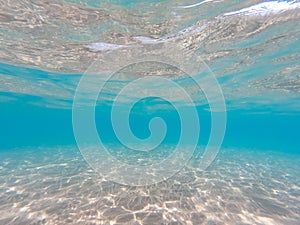 Underwater background with sandy sea bottom. Beautiful texture of the sea and ocean water. Pure water texture