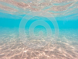 Underwater background with sandy sea bottom. Beautiful texture of the sea and ocean water. Pure water texture