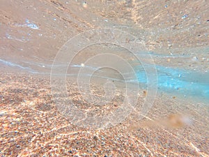 Underwater background with sandy sea bottom. Beautiful texture of the sea and ocean water. Pure water texture