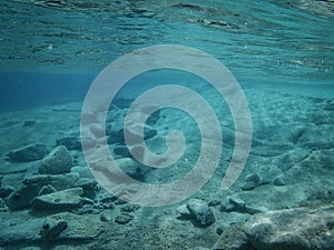 Underwater background, water surface and stony ocean floor