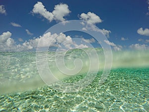 Underwater and blue sky - scuba diving, snorkeling concept - above and below ocean water surface