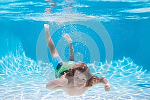 Underwater boy in the swimming pool. Cute kid boy swimming in pool under water. Summer kids activity, watersports.