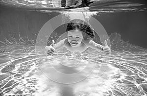 Underwater child swim in water swimming pool has fun under water on summer vacation.