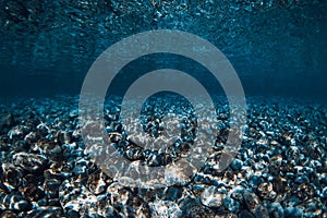 Underwater crystal ocean with stone bottom and reflection on surface