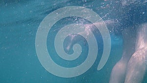 Underwater footage of body parts swimming in the sea. Beach.