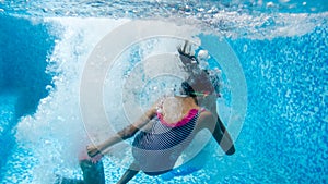 Underwater image of two teenage girl jumping and diving in swimming pool at gym