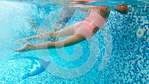 Underwater image of two teenage girls diving and swimming underwater at swimming pool