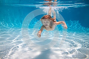 Underwater kid boy swim under water in swimming pool.