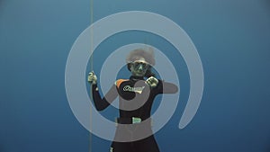 Underwater model free diver swims with red buoy in clean blue water in Red Sea.