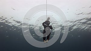 Underwater model free diver swims with red buoy in clean blue water in Red Sea.