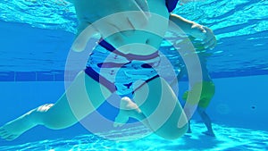 Underwater perspective of swimming in the hotel pool. Young caucasian child swimming with air swim sleeves for safety