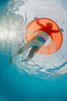 Underwater photo of girl swimming with fun on inflatable tube