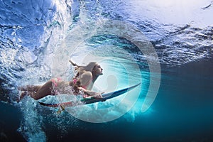Underwater photo of girl with board dive under ocean wave