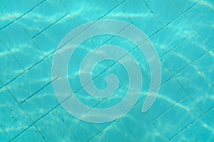 Underwater photo - old swimming pool bottom. Blue tiles pattern visible on floor. Abstract water background