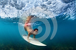 Underwater photo of surfer girl on surf board in ocean