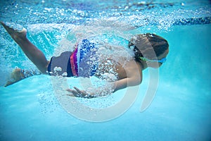 Underwater photo of a Young Boy swimmer in the Swimming Pool with Goggles.