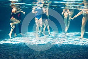 Underwater photo of young friends in swimming pool.