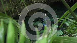 Underwater photographer. Man slowly swims underwater with professional camera